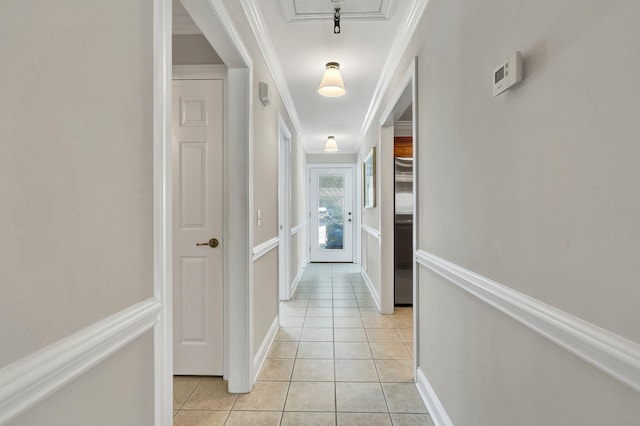 hallway with light tile patterned floors, baseboards, and ornamental molding