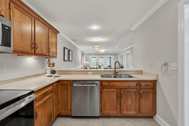 kitchen with a sink, appliances with stainless steel finishes, a peninsula, and brown cabinetry