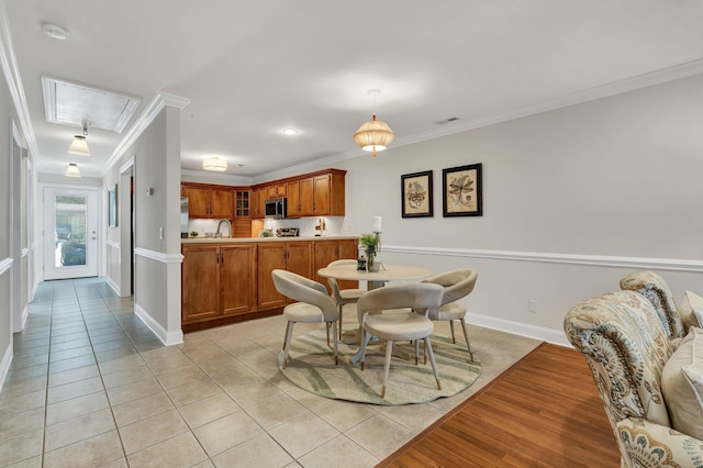 dining area with attic access, light tile patterned floors, crown molding, and baseboards