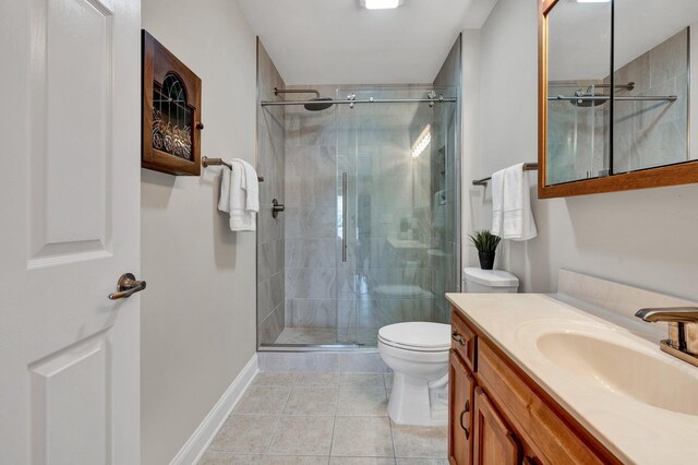 full bathroom featuring vanity, baseboards, a stall shower, tile patterned floors, and toilet