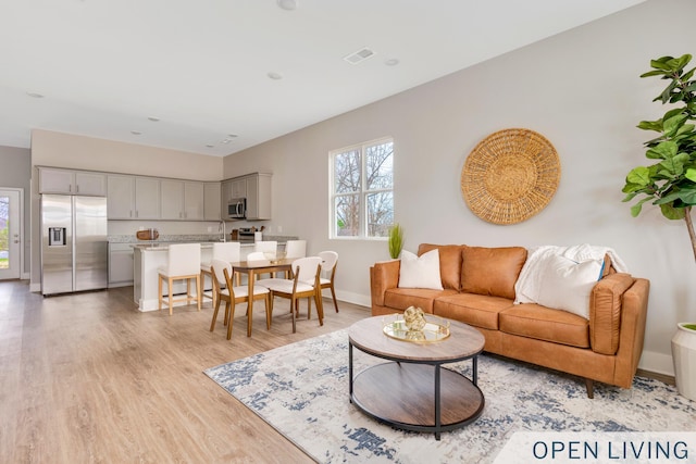 living area with visible vents, baseboards, and light wood-style flooring