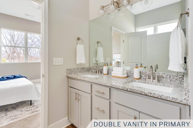 bathroom featuring double vanity, baseboards, and a sink