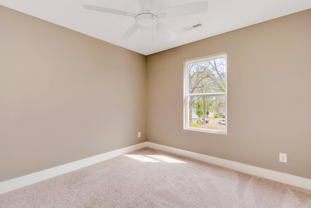 carpeted spare room featuring visible vents, baseboards, and ceiling fan