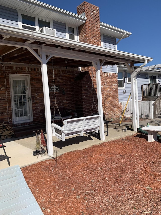 exterior space with a patio area, a chimney, and brick siding