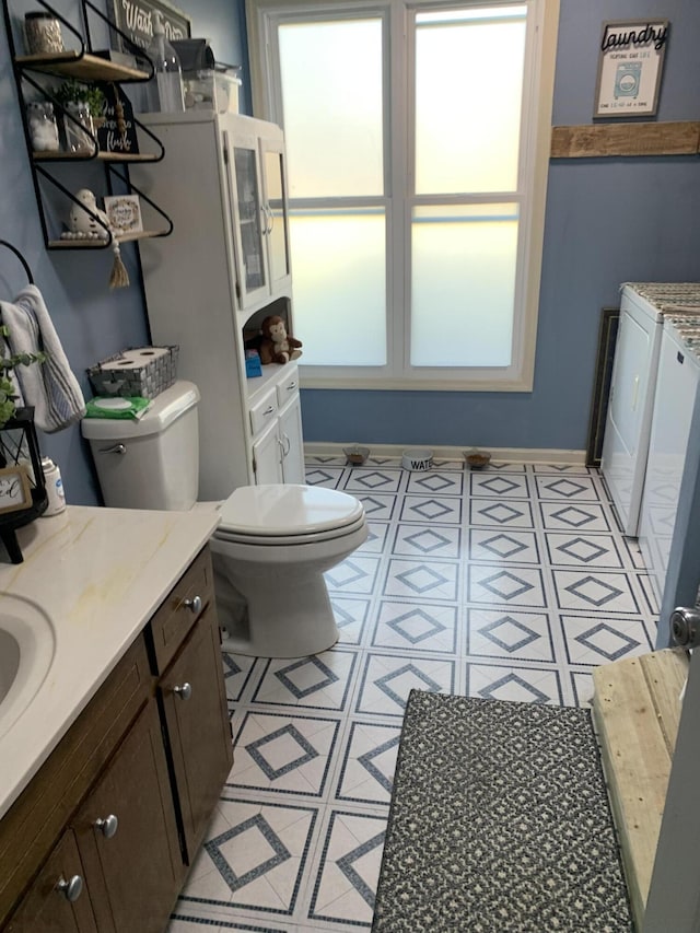 bathroom featuring washing machine and clothes dryer, toilet, and baseboards