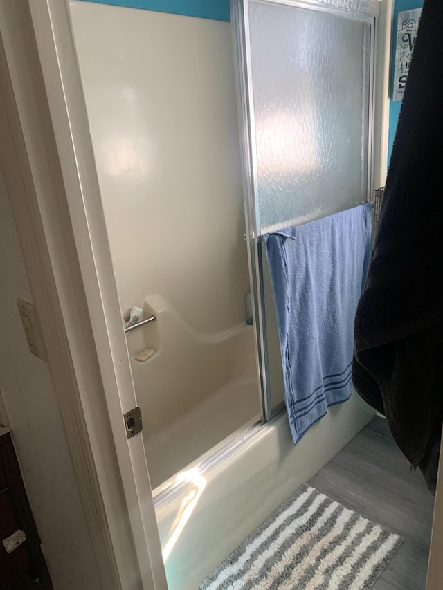 bathroom with shower / bath combination with glass door and wood finished floors