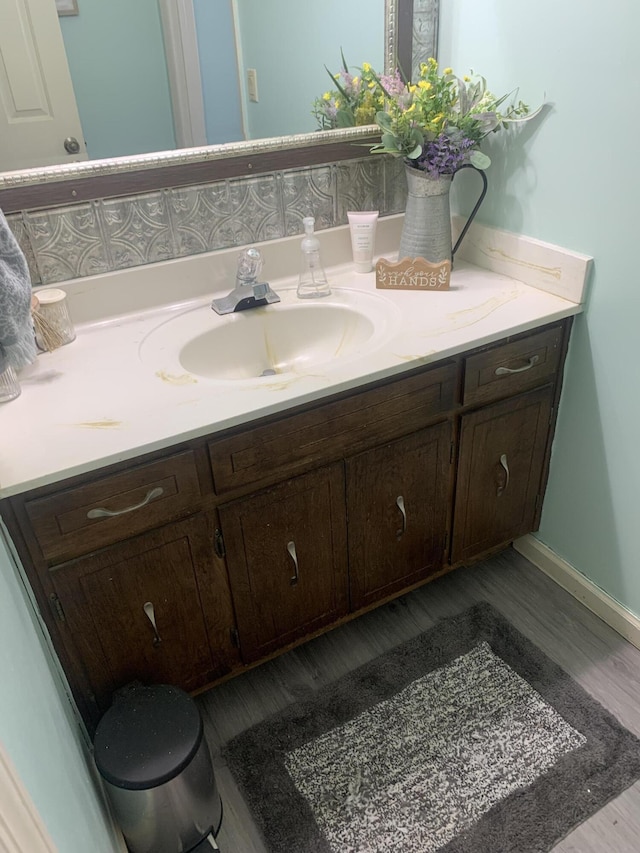 bathroom with baseboards, wood finished floors, and vanity