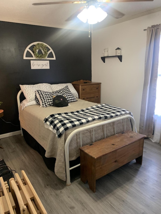 bedroom with ceiling fan, wood finished floors, baseboards, and ornamental molding