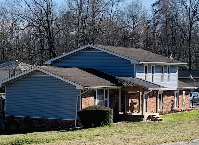 view of front facade with a front lawn, covered porch, and brick siding