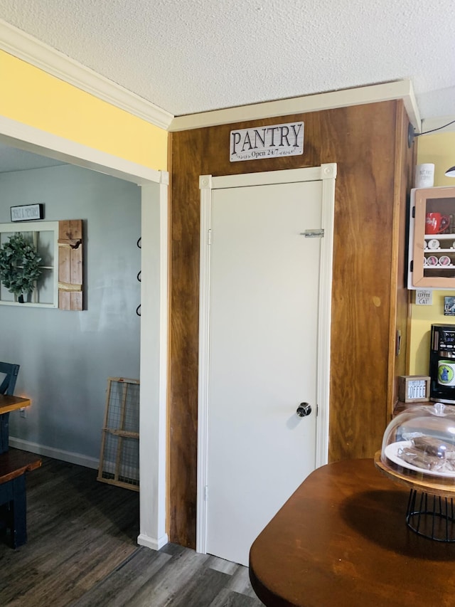 interior space with ornamental molding, wood finished floors, baseboards, and a textured ceiling