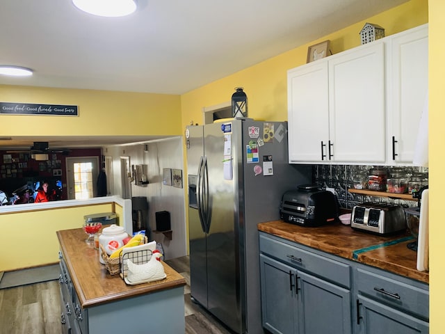 kitchen featuring white cabinets, wooden counters, wood finished floors, and stainless steel fridge