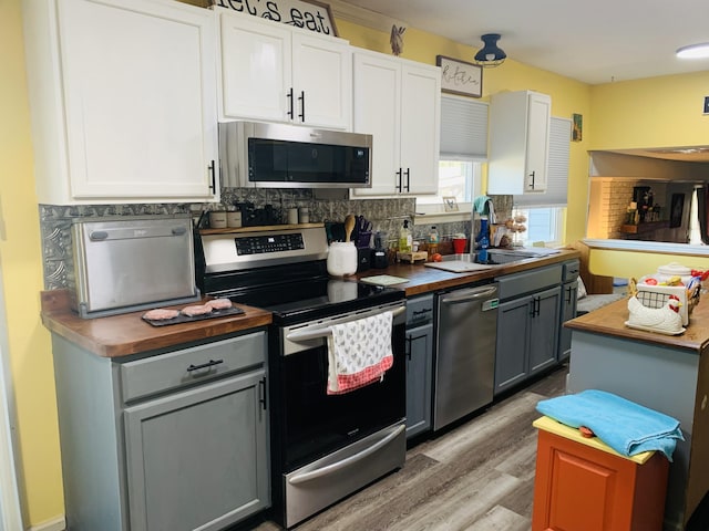 kitchen with tasteful backsplash, white cabinetry, stainless steel appliances, and a sink