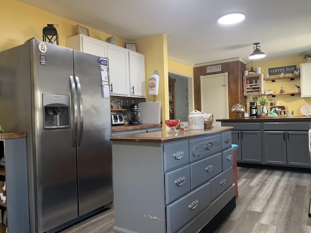 kitchen featuring wood finished floors, stainless steel fridge, a kitchen island, and white cabinets