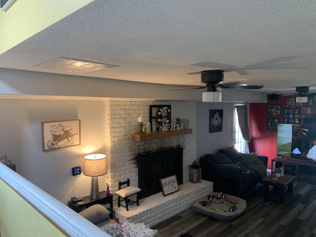 living room with a fireplace, ceiling fan, wood finished floors, and a textured ceiling