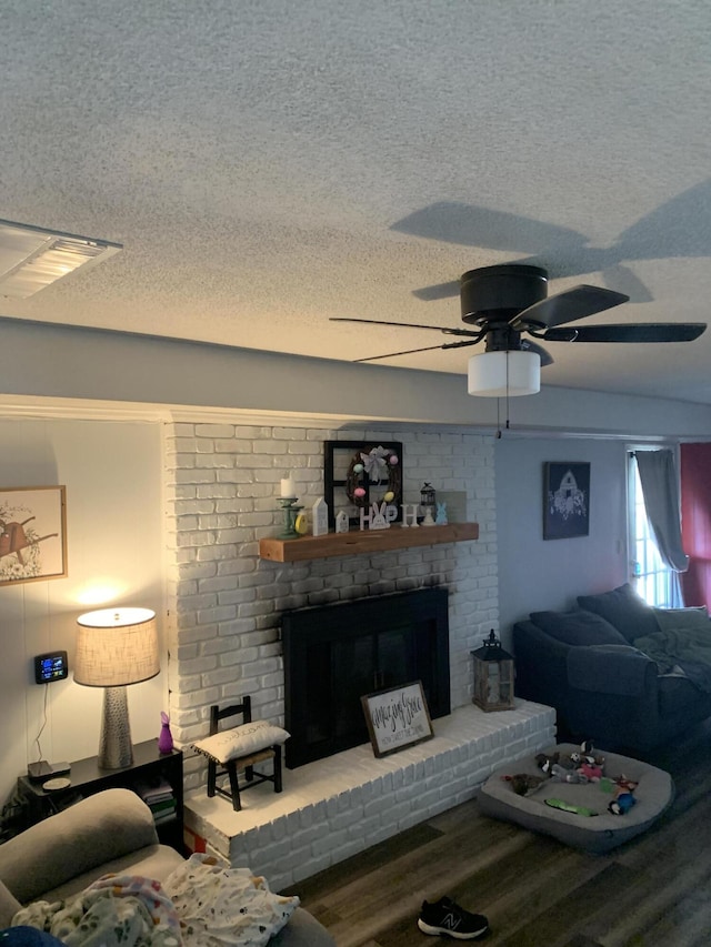 living room with visible vents, a textured ceiling, wood finished floors, and a fireplace