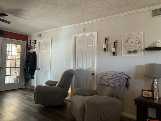 living area featuring visible vents, crown molding, dark wood-type flooring, a textured ceiling, and a ceiling fan