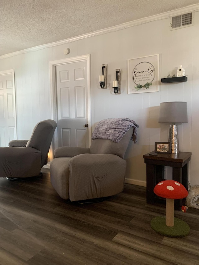 living area with crown molding, visible vents, dark wood-style flooring, and a textured ceiling