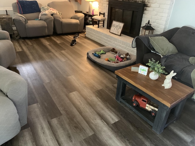 living area featuring a brick fireplace and wood finished floors