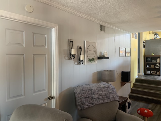 sitting room featuring visible vents, a textured ceiling, crown molding, and wood finished floors