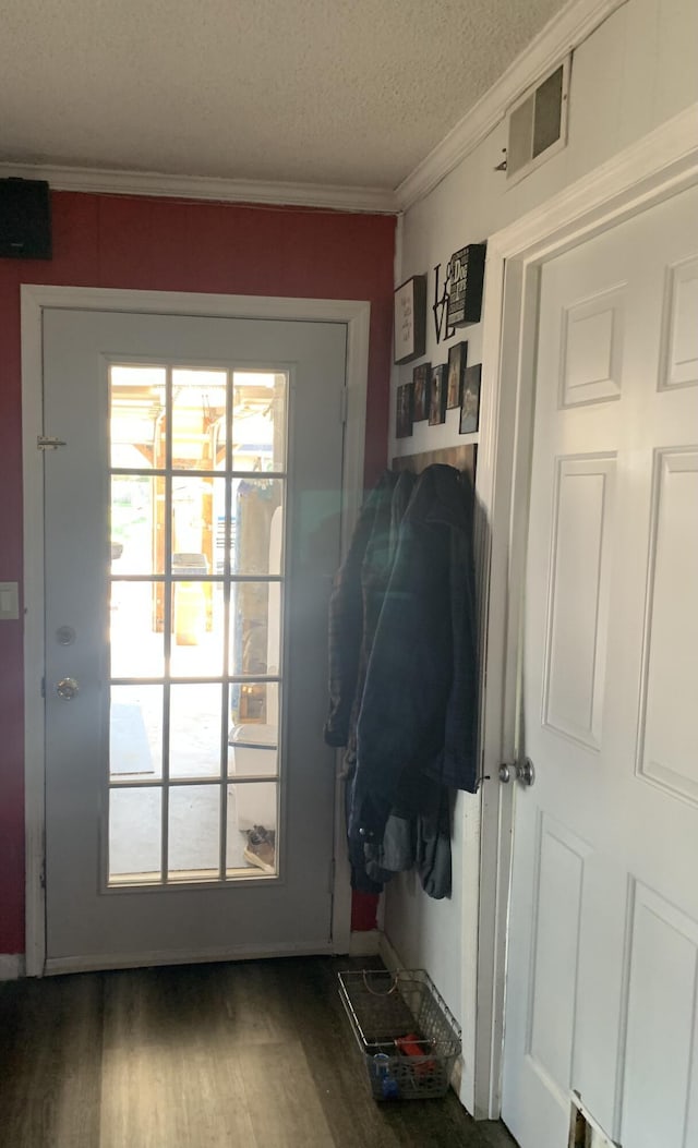 doorway to outside with visible vents, wood finished floors, a textured ceiling, and ornamental molding