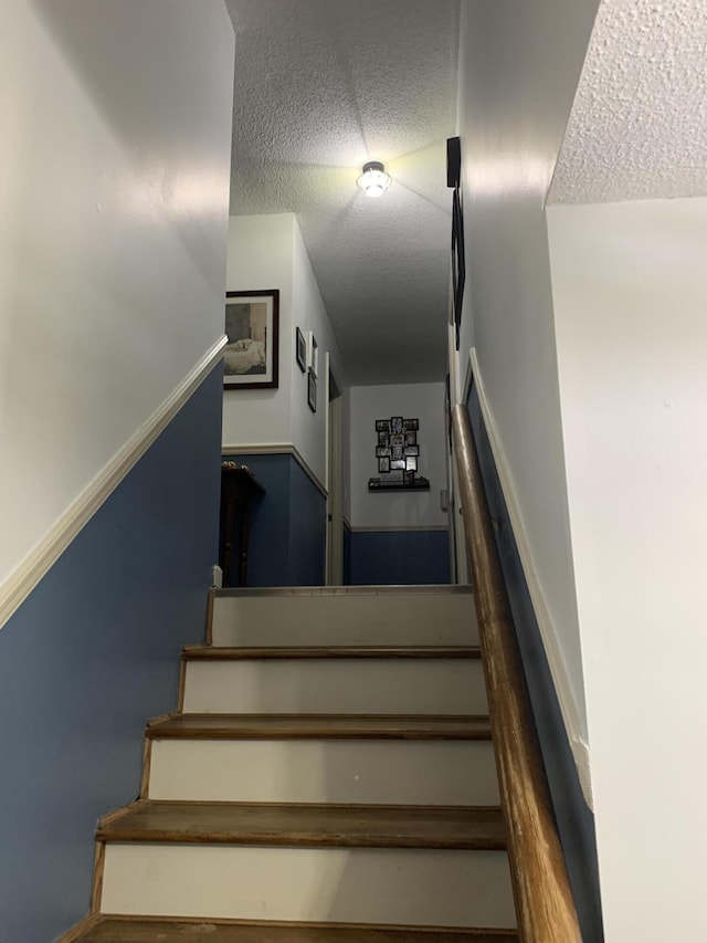 staircase with a textured ceiling