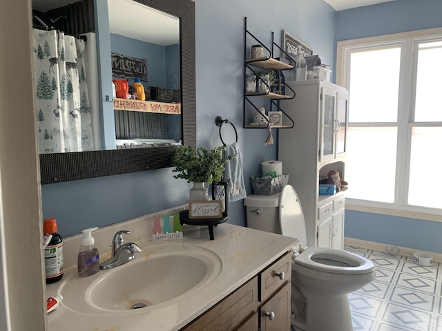 bathroom featuring plenty of natural light, toilet, vanity, and baseboards