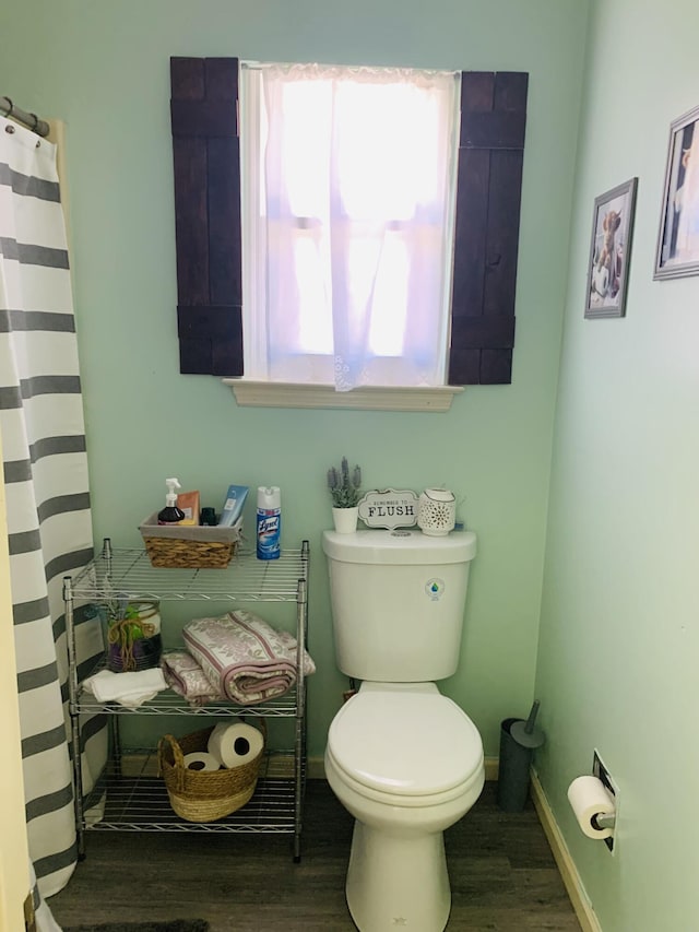 full bathroom featuring toilet, a shower with shower curtain, baseboards, and wood finished floors