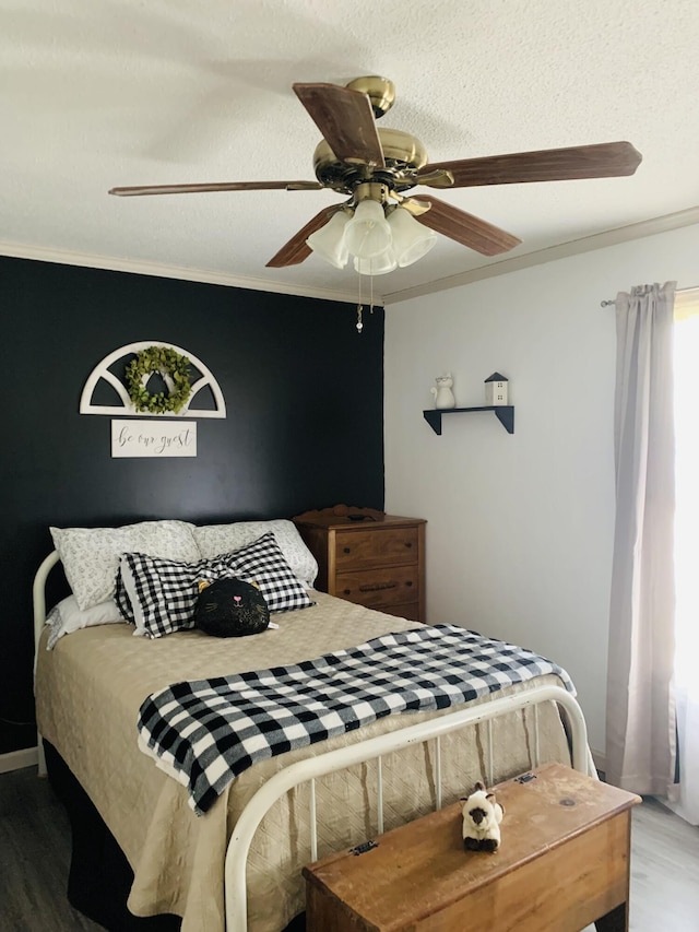 bedroom with ceiling fan, wood finished floors, a textured ceiling, and ornamental molding