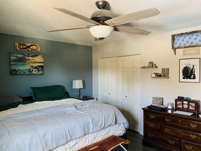 bedroom with dark wood-type flooring, a ceiling fan, a closet, and a textured ceiling