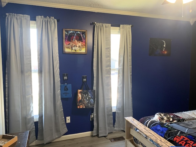 bedroom featuring ceiling fan, baseboards, wood finished floors, and crown molding