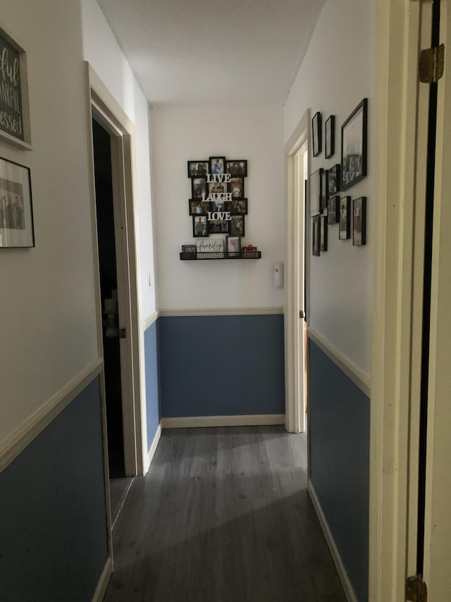 corridor with dark wood-type flooring and baseboards