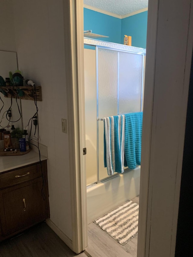 bathroom with combined bath / shower with glass door, a textured ceiling, and wood finished floors