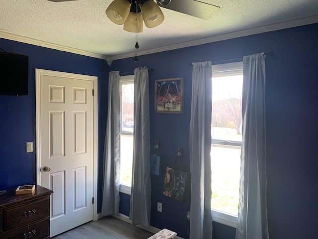 bedroom with ceiling fan, crown molding, light wood-style flooring, and a textured ceiling