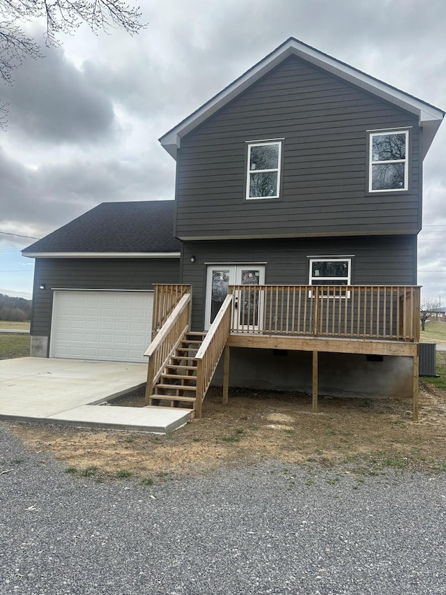 back of property featuring a shingled roof, concrete driveway, an attached garage, cooling unit, and a wooden deck