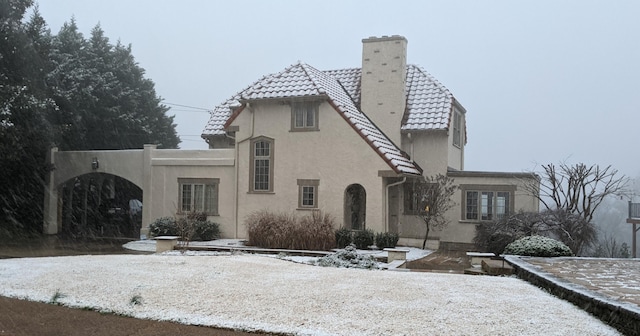 view of front of home with stucco siding, a chimney, and a tiled roof