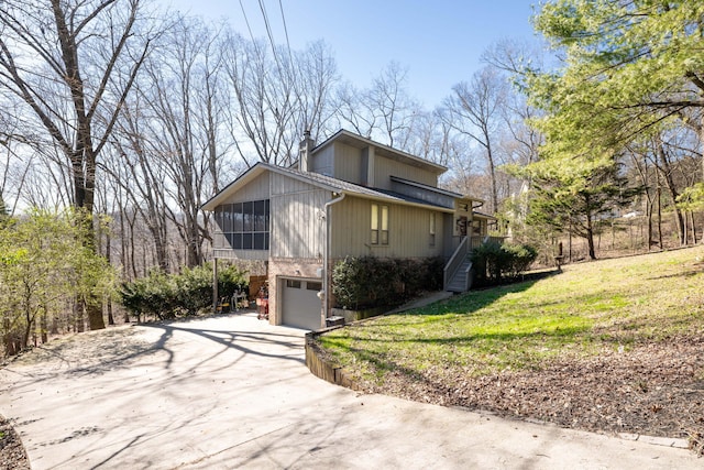 view of front of home with a garage, a sunroom, concrete driveway, a chimney, and a front yard