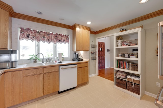 kitchen with a sink, crown molding, light countertops, and dishwasher