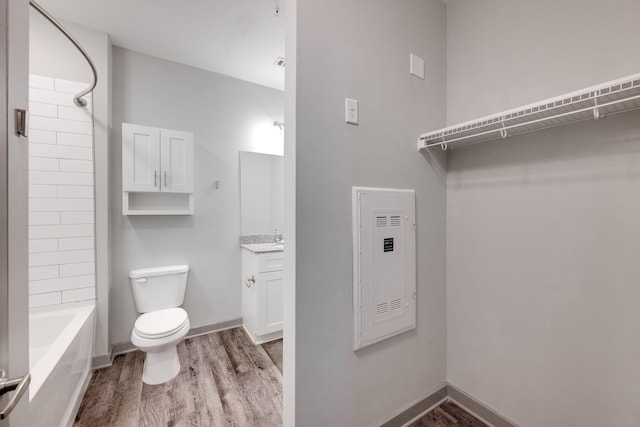 bathroom featuring shower / washtub combination, toilet, vanity, wood finished floors, and baseboards