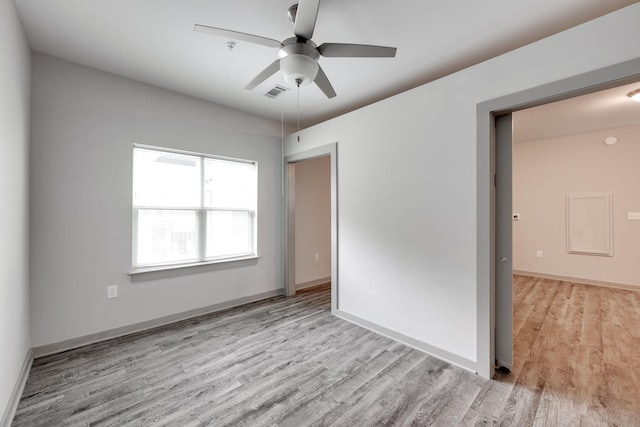 empty room featuring light wood-type flooring, visible vents, and baseboards