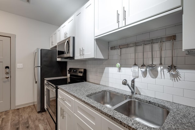 kitchen with tasteful backsplash, appliances with stainless steel finishes, white cabinets, and a sink