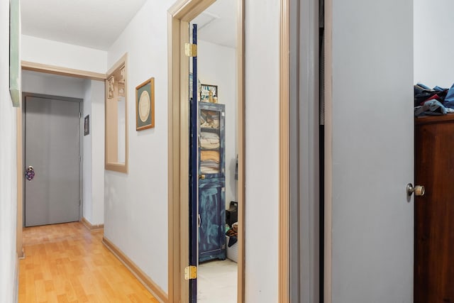 corridor with light wood-style floors and baseboards