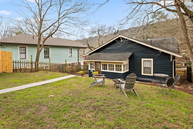 rear view of property featuring a yard and fence