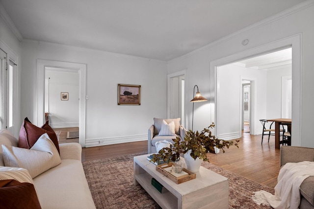 living area featuring baseboards, visible vents, ornamental molding, and wood finished floors