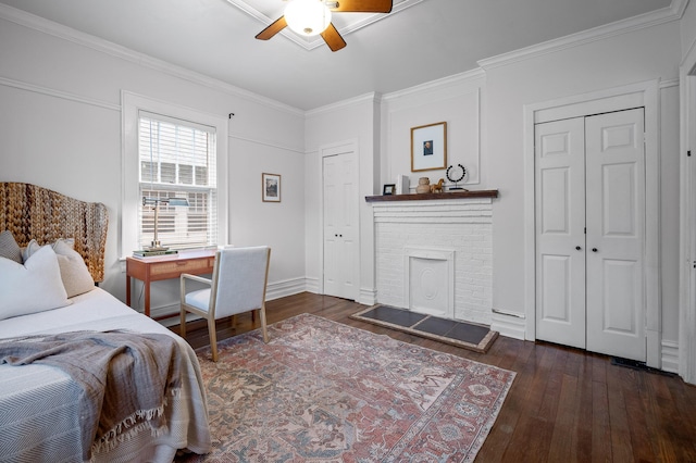 bedroom with a fireplace, crown molding, multiple closets, ceiling fan, and hardwood / wood-style floors