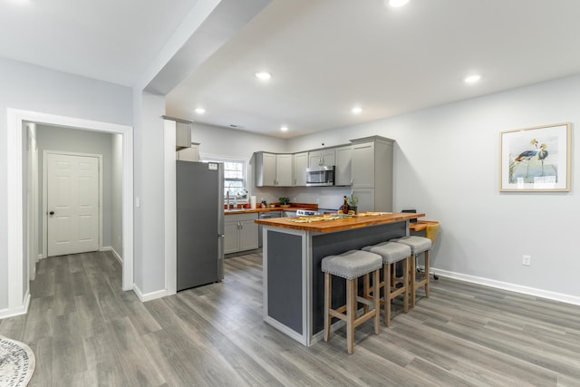 4513 Lamont Ln, Chattanooga, TN 37415 - kitchen featuring light wood finished floors, gray cabinets, stainless steel appliances, a kitchen breakfast bar, and butcher block counters