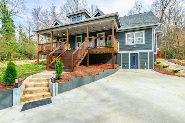 view of front of property featuring stairway, concrete driveway, a ceiling fan, and a shingled roof