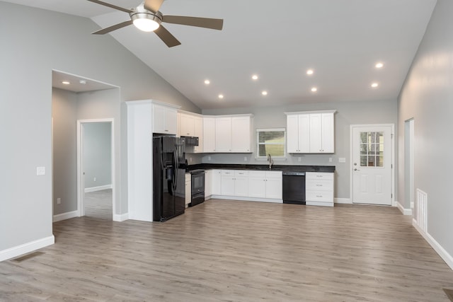 kitchen with visible vents, dark countertops, open floor plan, black appliances, and a sink