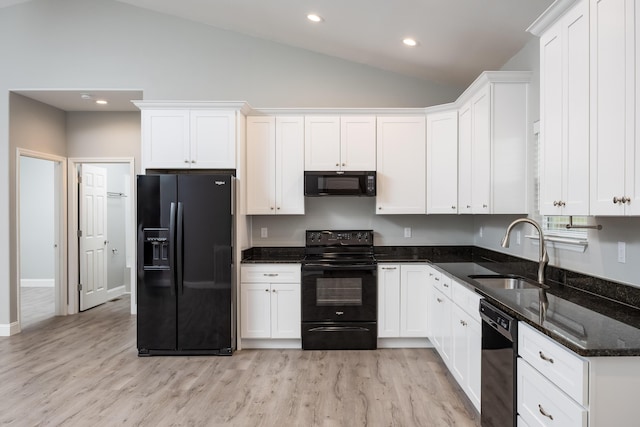 kitchen featuring lofted ceiling, white cabinetry, a sink, and black appliances