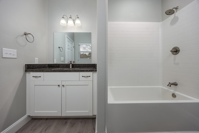 bathroom with bathtub / shower combination, vanity, baseboards, and wood finished floors