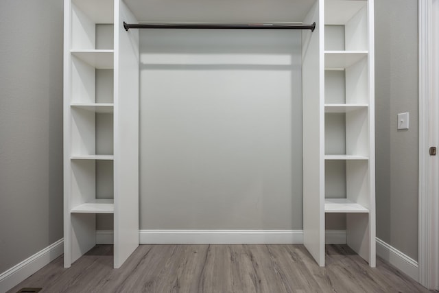 walk in closet with wood finished floors